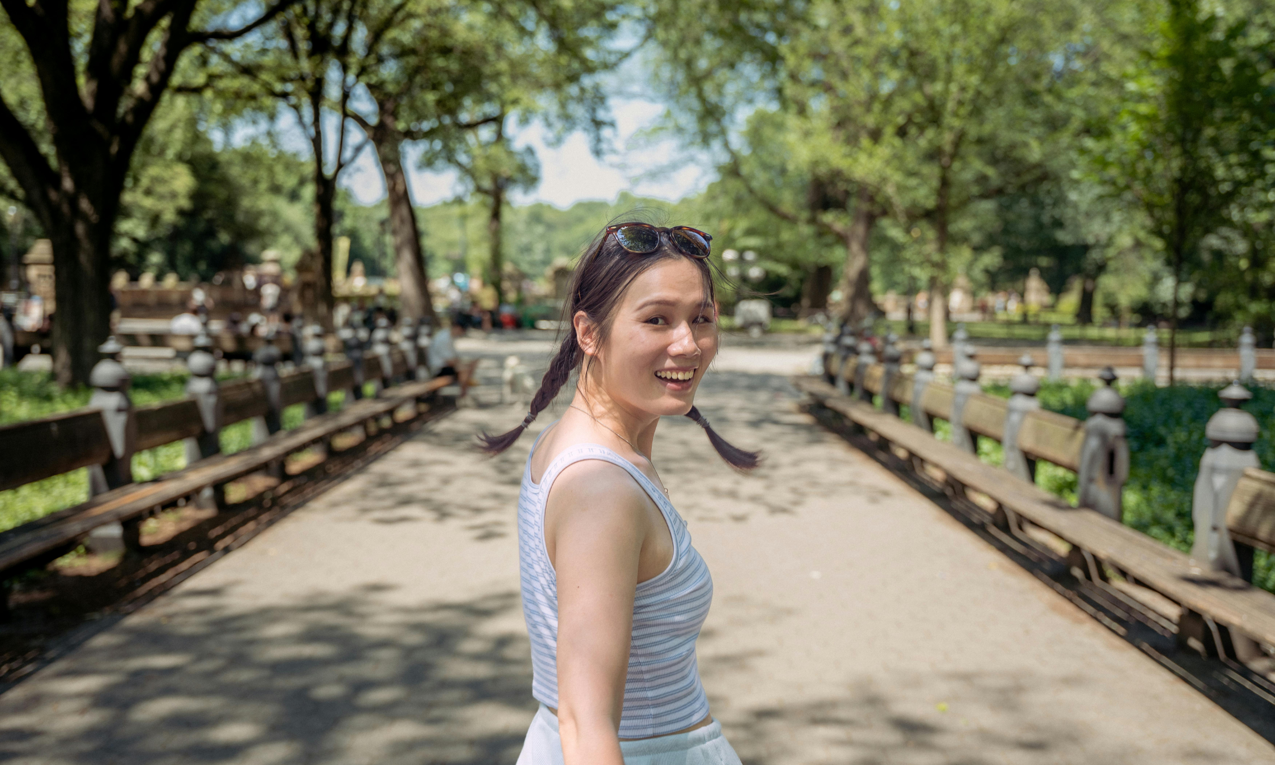 A woman in a white tank top and sunglasses walks on a path, illustrating the journey of Cognitive Behavioral Therapy in NYC