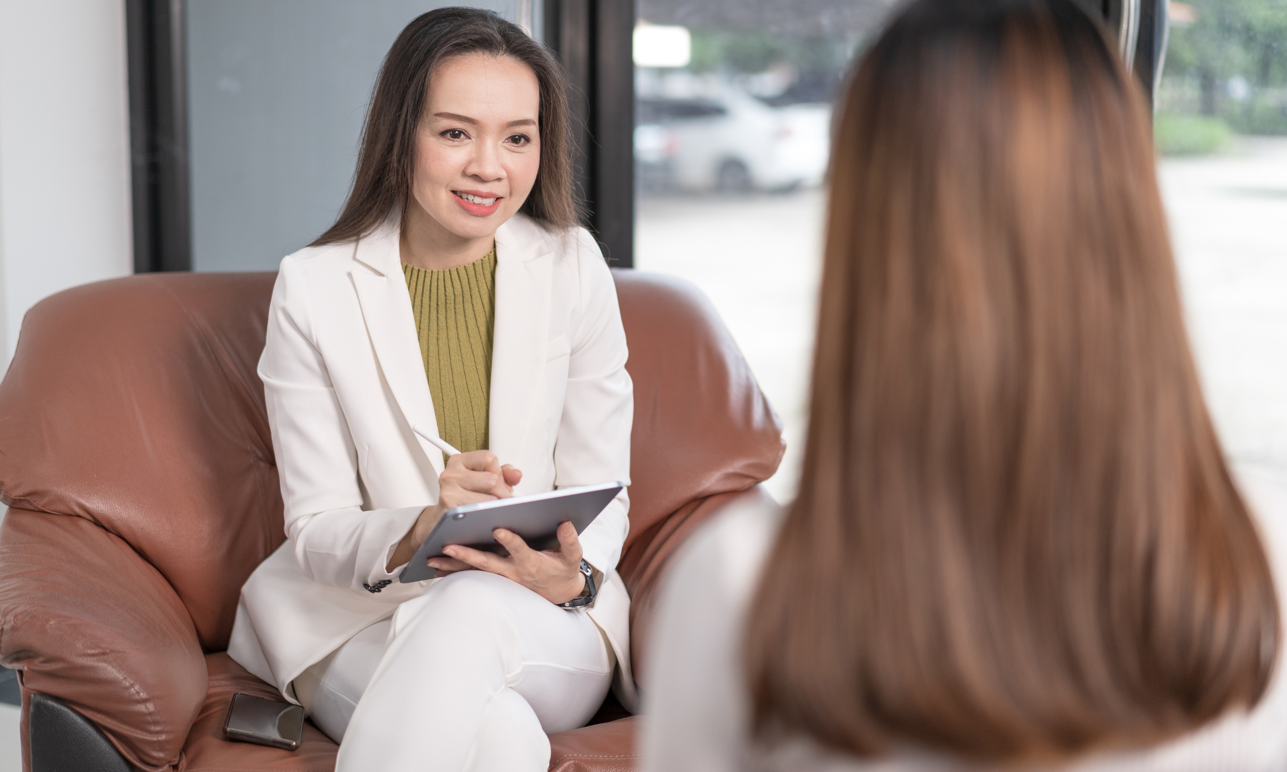 Professional CBT counselor in NYC, discussing therapy approaches with a patient, modern therapist office, compassionate expression, natural daylight
