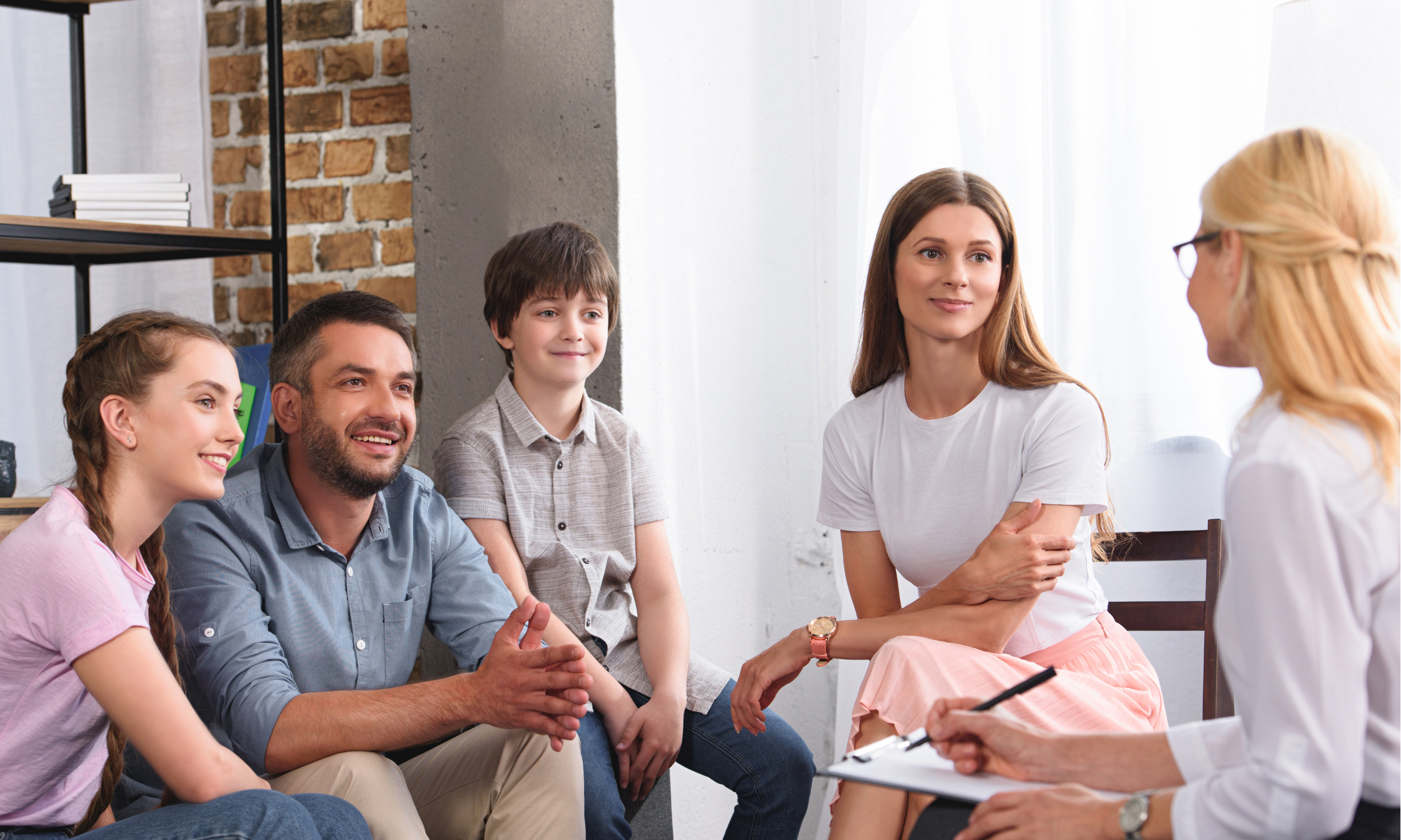 A family engages in conversation with a therapist in a cozy room, focusing on their emotional well-being