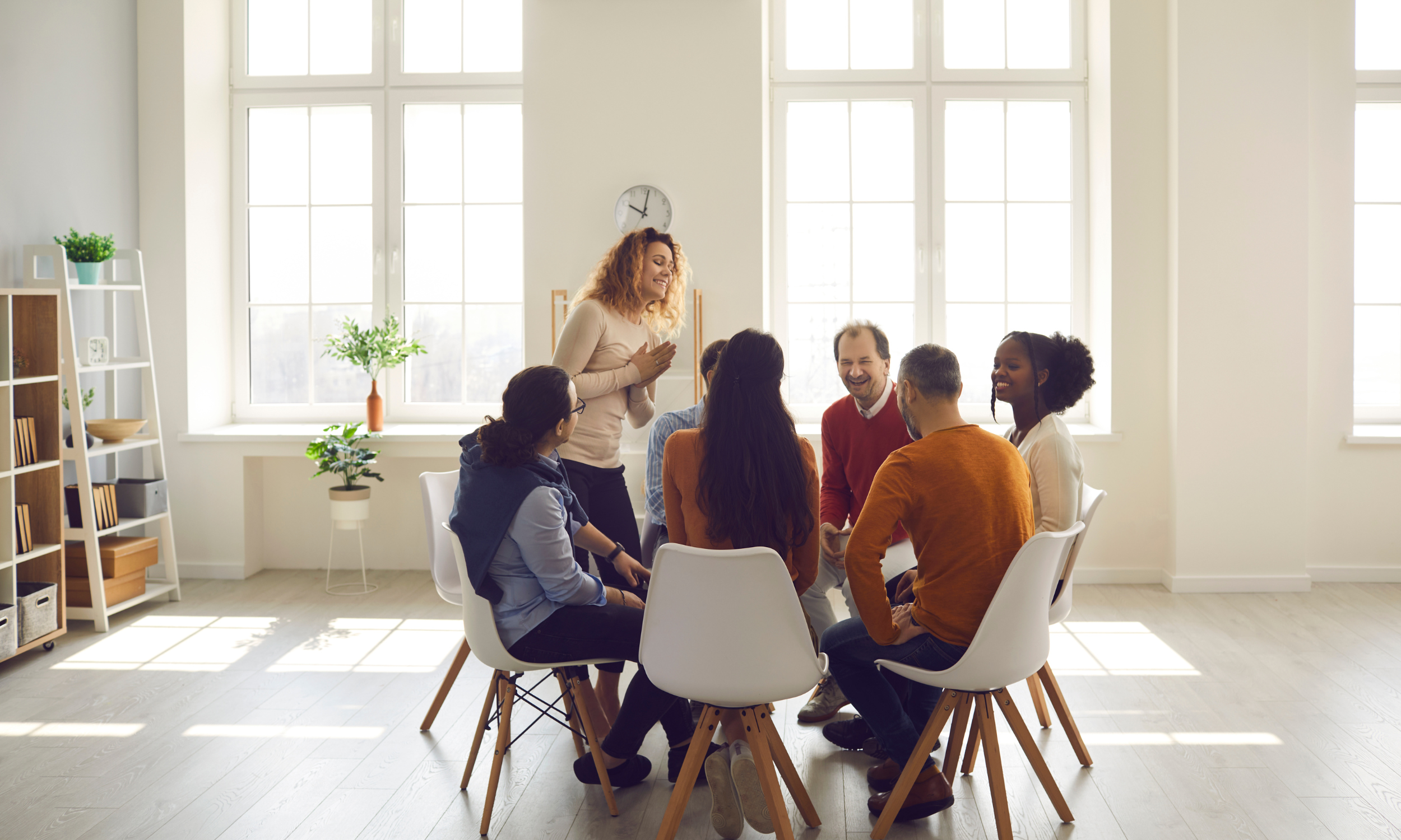 A group of people engaged in a therapy session, sitting around a table in a professional office setting