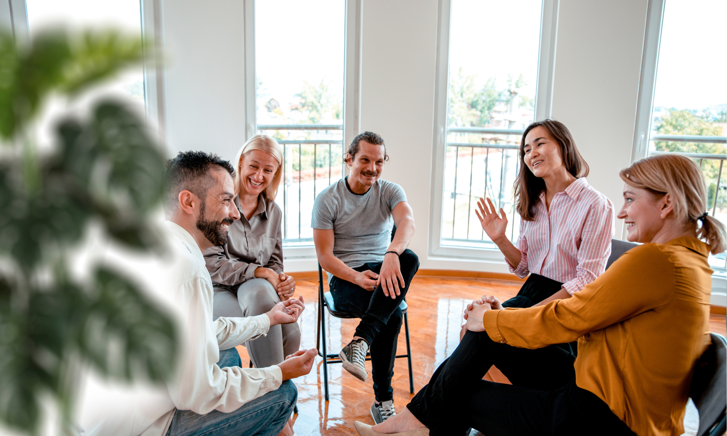 A group of people engaged in conversation around a table during a therapy session.